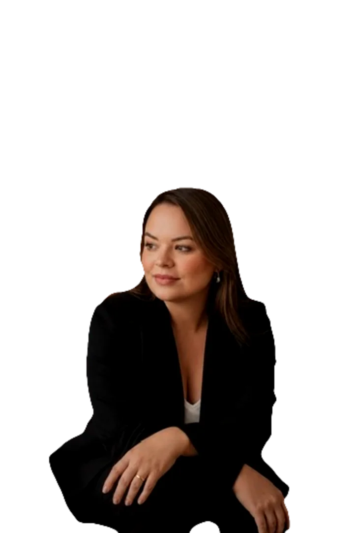 Bruna Araújo sentada, de blazer preto, olhando para o lado.
